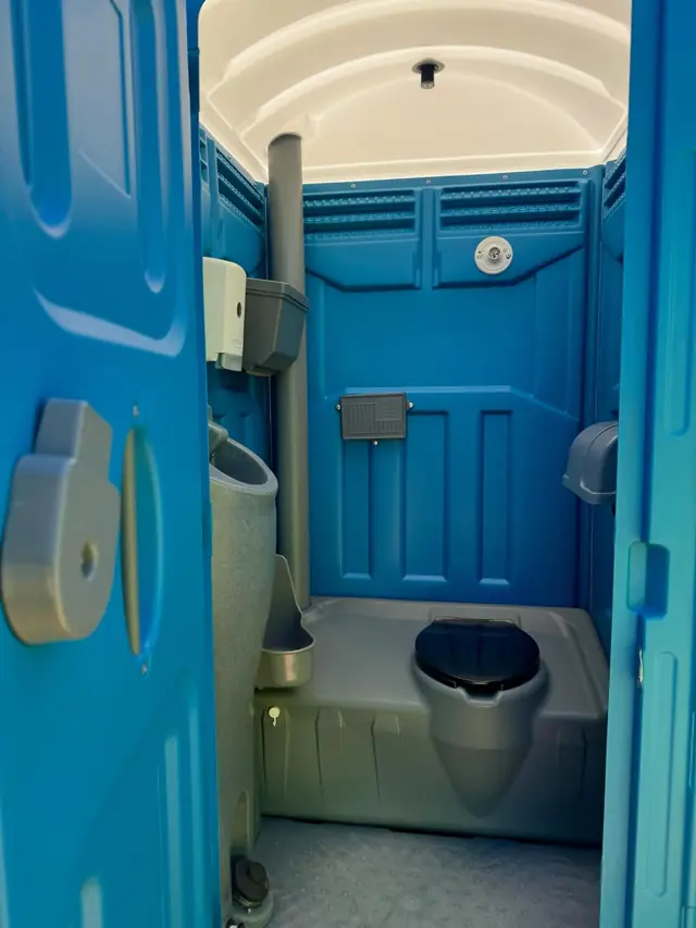Blue deluxe porta potty with its door open showing the clean interior