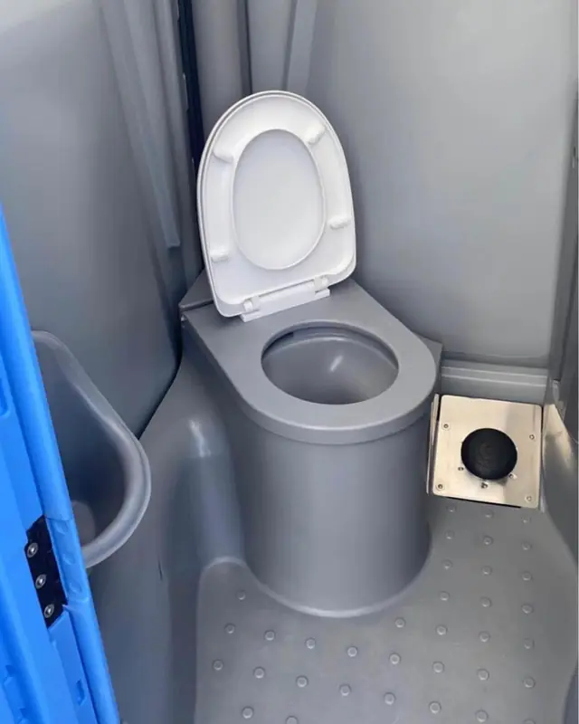Gray deluxe porta potty interior with a toilet seat and wall dispensers