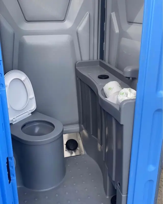 Deluxe porta potty interior with soap and towel dispensers above the seat