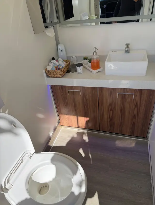 Restroom trailer vanity with a vessel sink and wood cabinet