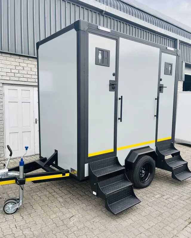 Gray two-stall restroom trailer with steps at each door