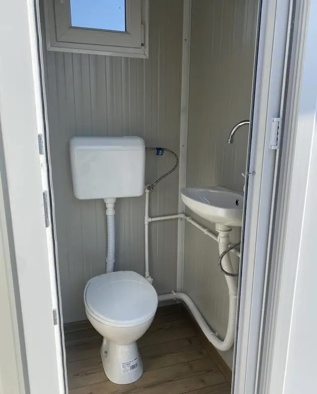 Inside a VIP restroom with a flush toilet, wall tank and small sink