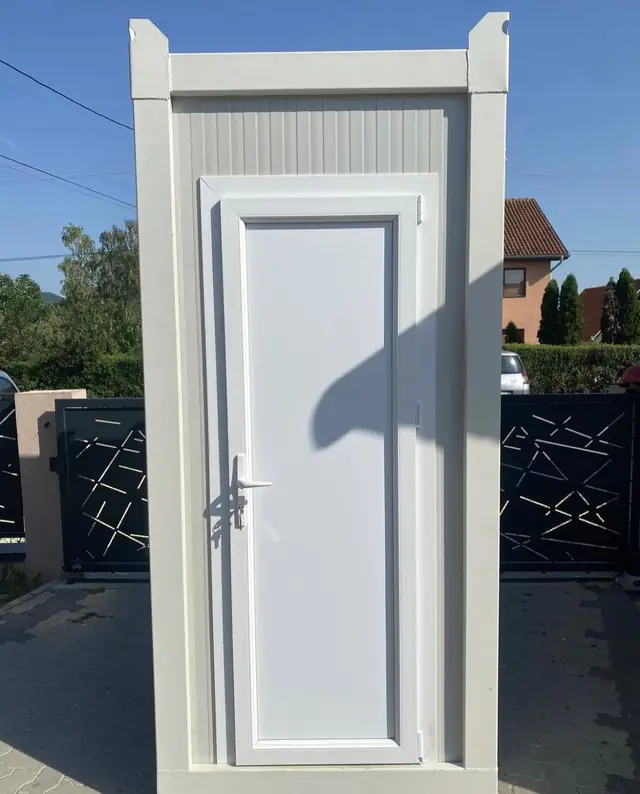 White VIP restroom unit standing on pavers beside a house